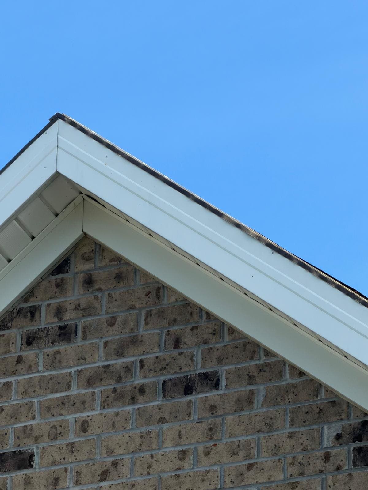 Close view of clean white fascia and roof edge against a blue sky on a finished Avon roof