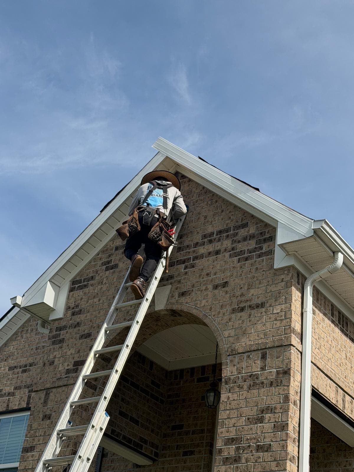Roofer climbing a ladder to the roof of a brick home in Avon, Indiana